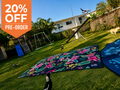 Floral outdoor mat on grass with birds, dog, and kids' play equipment — perfect for picnics, camping, or beach days.