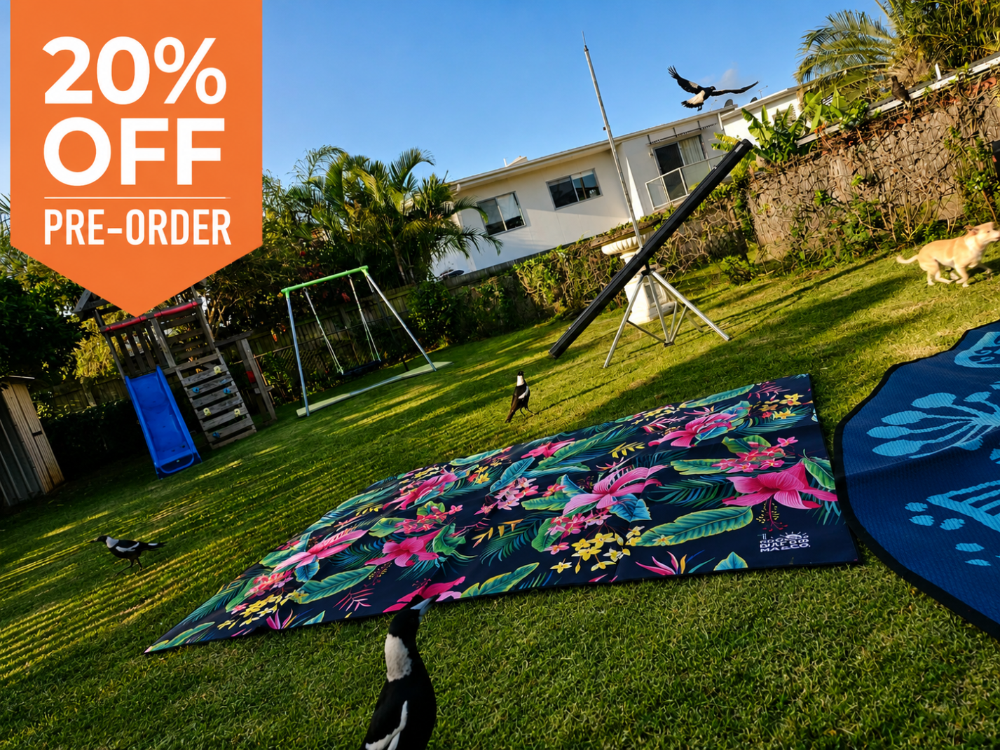 Floral outdoor mat on grass with birds, dog, and kids' play equipment — perfect for picnics, camping, or beach days.