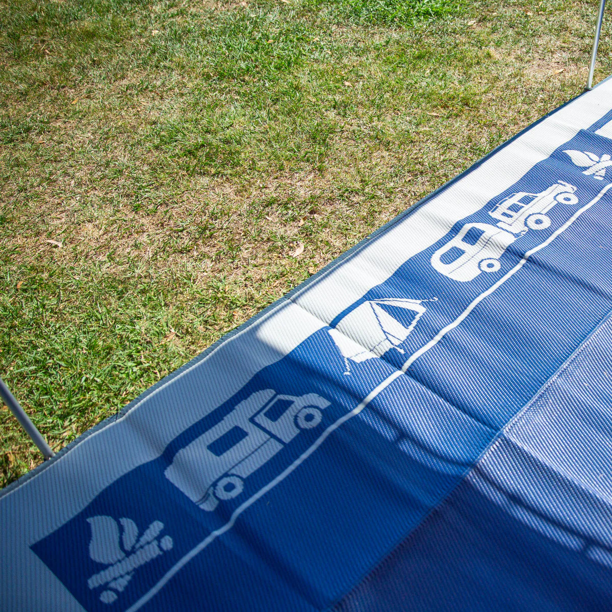 Blue recycled outdoor mat with caravan, tent, and camp icons on grass, perfect for camping and picnics.