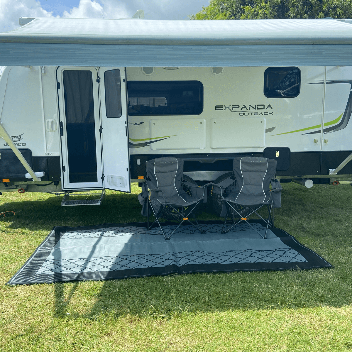 Recycled outdoor mat under caravan with camping chairs on grass, perfect for picnics and beach days