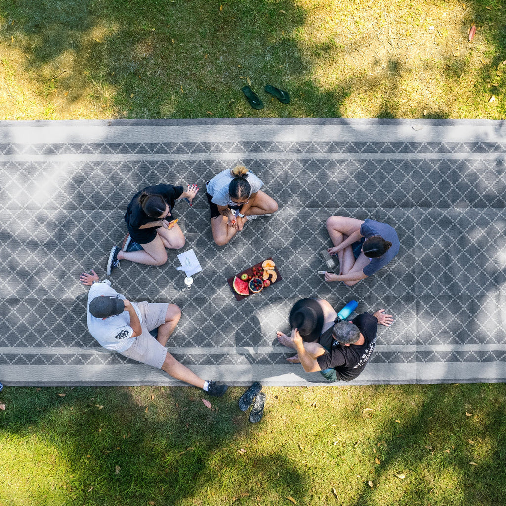 Group enjoying picnic on eco-friendly outdoor mat in park, perfect for picnics, camping, beach days