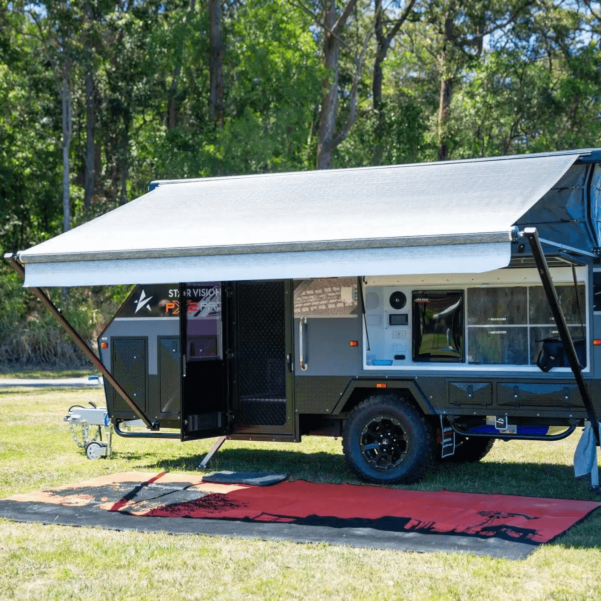 Red and black recycled outdoor mat under caravan awning on grass, perfect for camping and picnics
