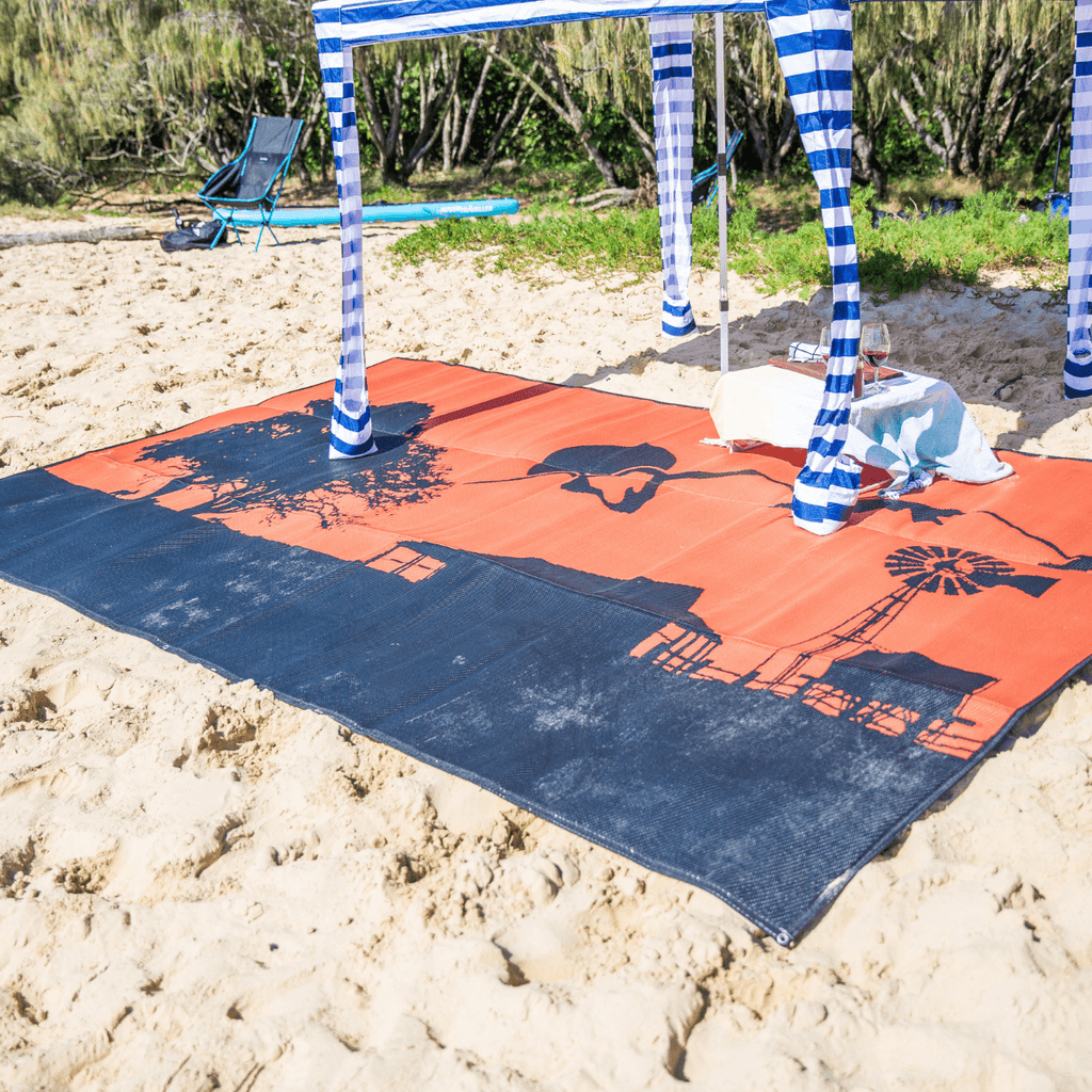 Orange and navy recycled outdoor mat on sandy beach under striped canopy, perfect for picnics and beach days