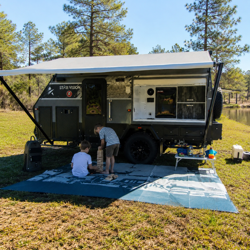 Kids playing Jenga on a recycled outdoor mat beside a caravan in a grassy campsite