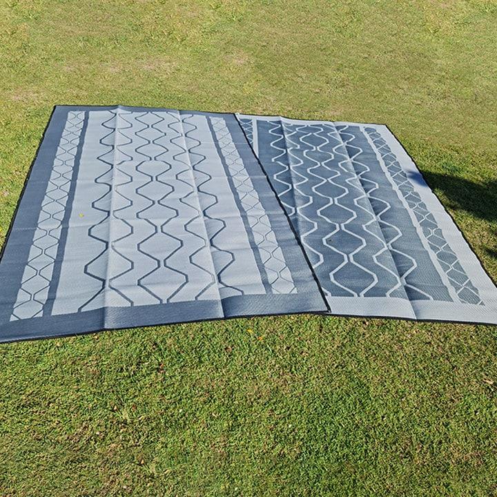 Recycled outdoor mat with geometric pattern on grass, ideal for picnics, camping, and beach days