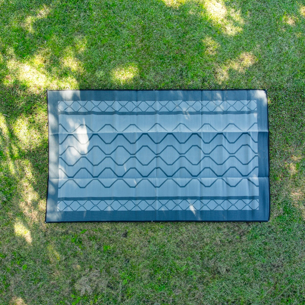 Recycled outdoor mat with geometric pattern on grass, ideal for picnics, camping, beach, or caravan use