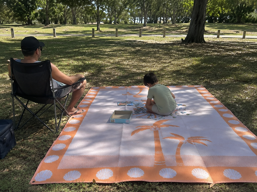 Family enjoying picnic on eco-friendly outdoor mat with palm tree design in park