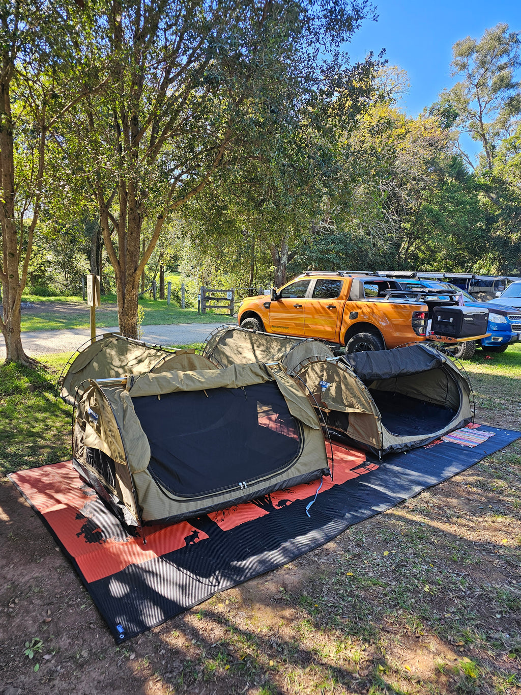 Eco-friendly outdoor mats under camping tents in a wooded campsite, perfect for grass and dirt.