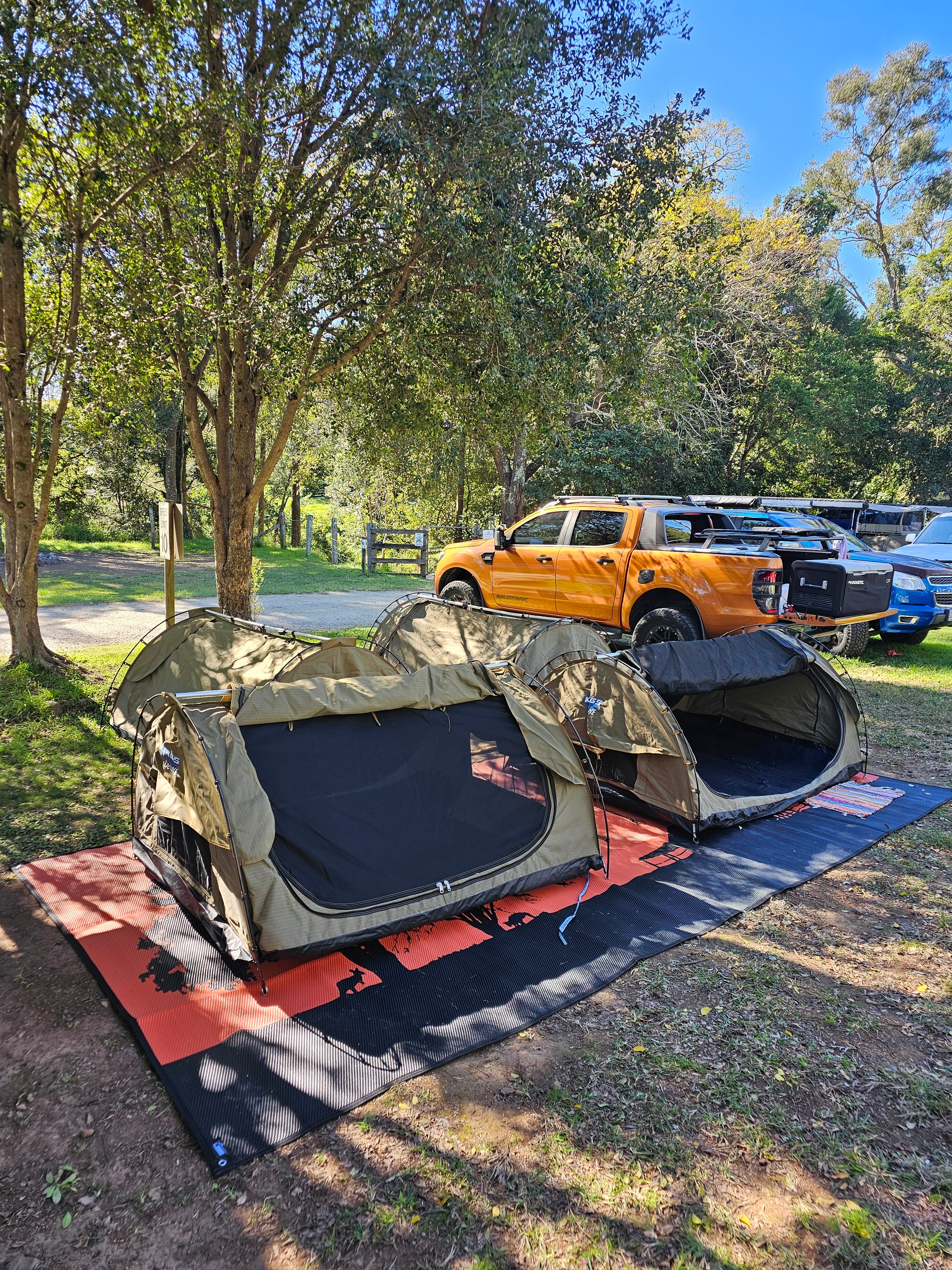 Eco-friendly outdoor mats under camping tents in a wooded campsite, perfect for grass and dirt.