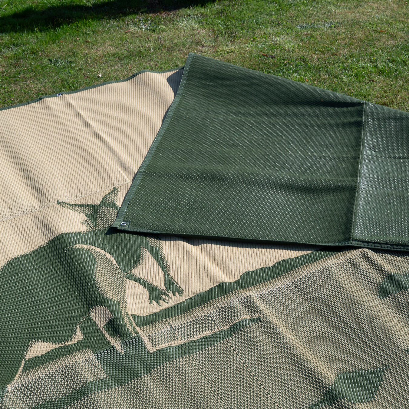 Camouflage outdoor mat on grass, ideal for camping, picnics, and beach days. Eco-friendly, recycled material.
