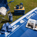 Blue recycled outdoor mat with camper van print, perfect for picnics, camping, or beach days with chair, lantern, and tumbler.