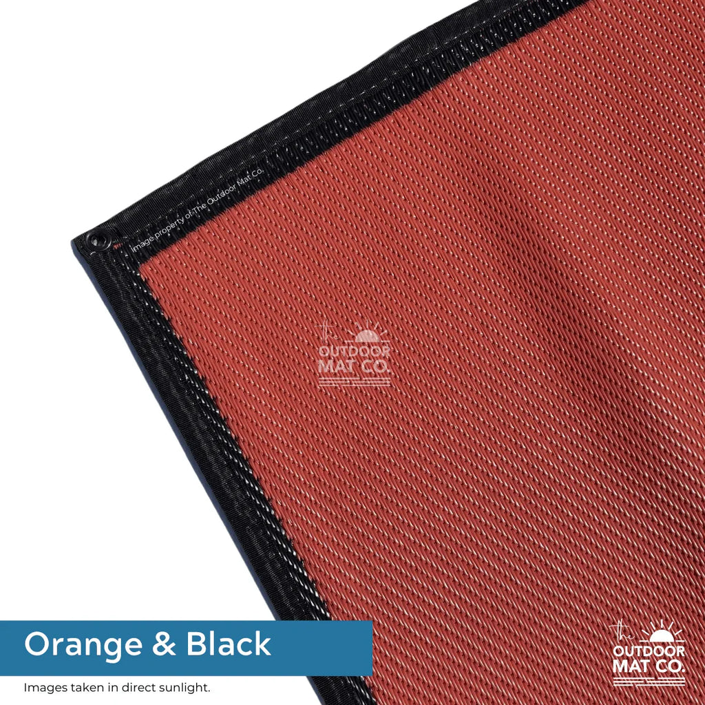 Orange and black recycled outdoor mat with durable woven texture and reinforced black border for camping, beach, or picnics.