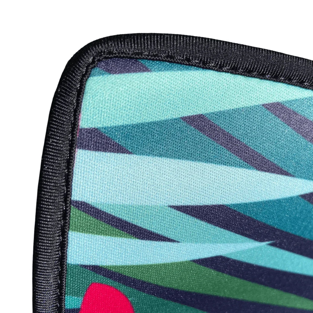 Close-up of durable outdoor mat with geometric teal, green, and navy pattern and black stitched edge